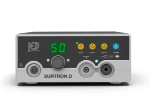 Front view of a Surtron D electrosurgical generator front panel: green numeric display shows 50, yellow indicator lights labeled CUT (1 and 2) and blue COAG, a central control knob, and multiple connector ports, with the brand name SURTRON D visible.